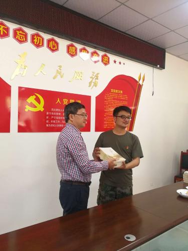 在小谷溪村向中纪委下派第一书记柴杰（右）赠送扶贫书籍